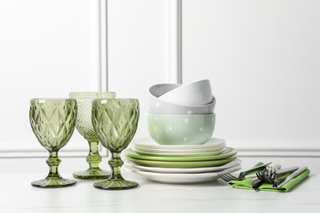 Beautiful ceramic dishware, glasses and cutlery on white marble table