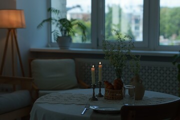 Clean dishware, flowers, fresh pastries and burning candles on table in stylish dining room