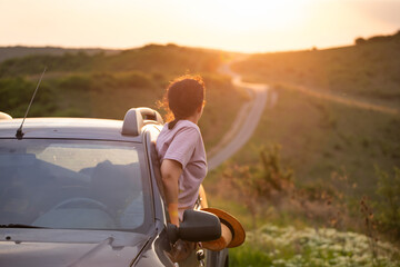 Fototapeta premium Girl with hat in the window of the car. Adventure, vacation, road trip concept.
