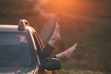 Summer travel concept with legs of a woman and car.