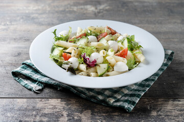 Pasta salad with vegetables and mozzarella cheese on wooden table