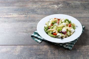 Pasta salad with vegetables and mozzarella cheese on wooden table. Copy space