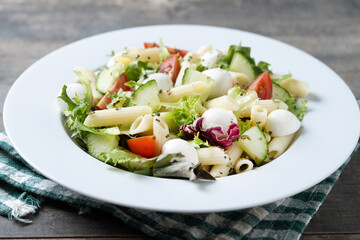 Pasta salad with vegetables and mozzarella cheese on wooden table
