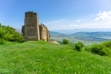 Fototapeta premium Landscape view and Skhvilo fortress. Windows and loopholes. Bushes and mountains. Bright sky