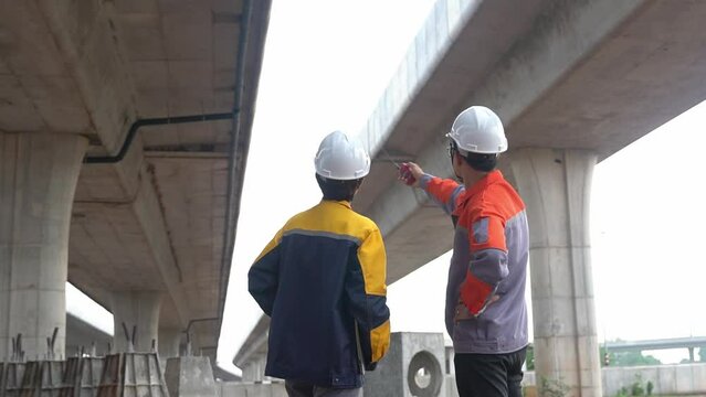 Back view of Asian male and female engineers Inspecting construction work radio command concrete road bridge highway