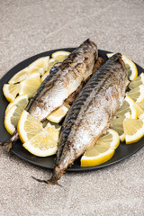 Oven-baked mackerel sea fish dish served with fresh lemon slices