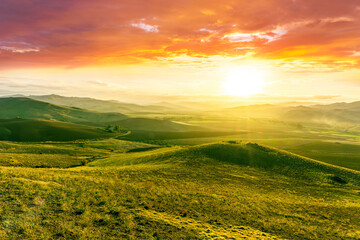 Fototapeta premium spring green field landscape in beautiful countryside with green and yellow grass, rural hills and amazing cloudy sky on background. Agriculture landscape with rural view