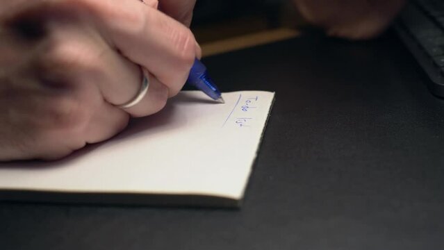 Extreme closeup shot of male hand taking notes on paper