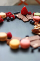 Macarons, chocolate, cookies, berries and various nuts on dark blue background. Selective focus.