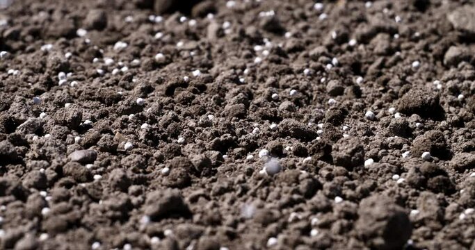 Super slow motion close up of natural bio fertilizers granules added for field ground soil by agricola machinery before plant in ecological rural farmland agricultural plantation at 1000 fps