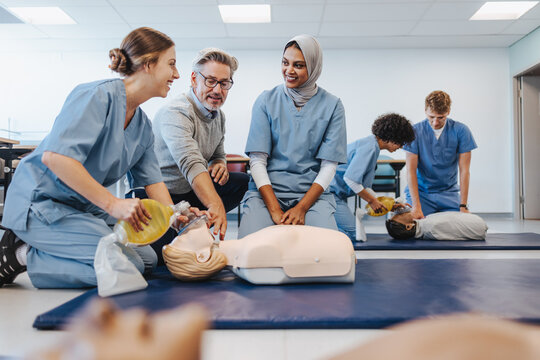 Mature doctor teaching students how to do CPR in a medical simulation