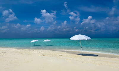 Summer tropical with white umbrella on the beach with  blue sky background