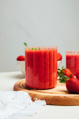 Fruit smoothie in transparent cups. Red strawberry smoothie on a concrete background. The concept of healthy eating. Front view