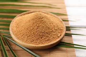 Coconut sugar, palm leaves and bamboo mat on wooden rustic table, closeup