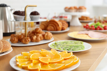 Different meals served on wooden table indoors, closeup. Buffet menu