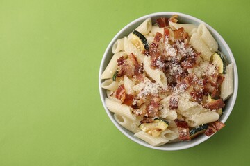 Tasty pasta with bacon and cheese on light green table, top view. Space for text