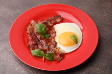 Fried egg, bacon and basil on brown table