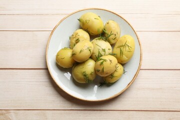 Tasty young boiled potatoes with dill on wooden table, top view