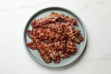 Slices of tasty fried bacon on white marble table, top view