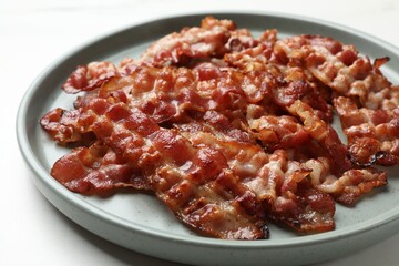 Slices of tasty fried bacon on white table, closeup