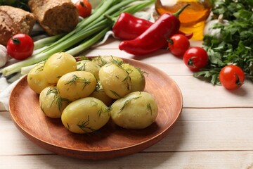 Tasty young boiled potatoes with dill and other products on wooden table