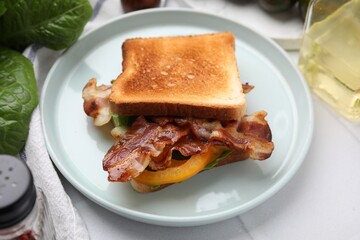 Tasty sandwich with bacon and bell pepper on white table