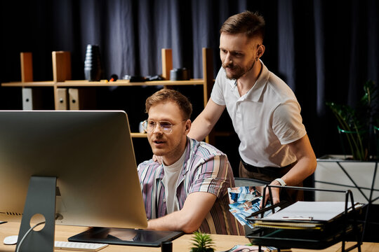 Two men engaged, captivated by data on a screen.