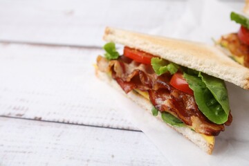 Delicious sandwiches with fried bacon on wooden rustic table, closeup. Space for text