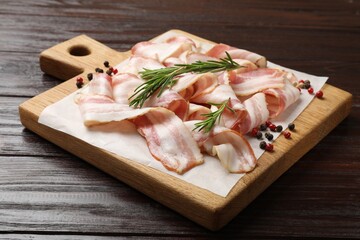 Slices of raw bacon and spices on wooden table, closeup