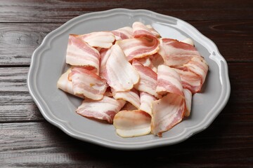 Slices of raw bacon on dark wooden table, closeup