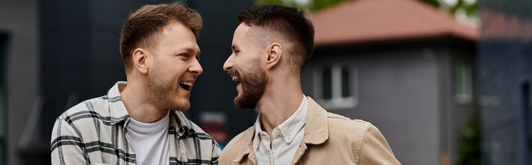 Fototapeta premium Two men in casual attire, happily standing side by side outdoors.
