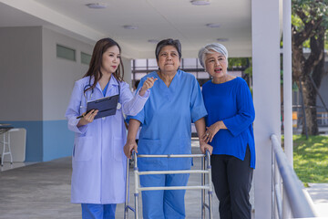 doctor or nurse helping Senior man to walk at nursing home with walker. Doctor or  nurse helping...