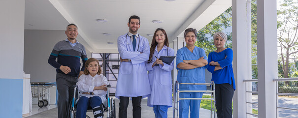 Doctors and nurse in hospital corridor with senior female and  senior male patient in walker and...