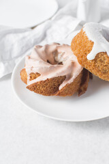 Iced mini bundt cake on a white plate, vanilla citrus bundlette on a plate, small vanilla bundt cake with an icing glaze