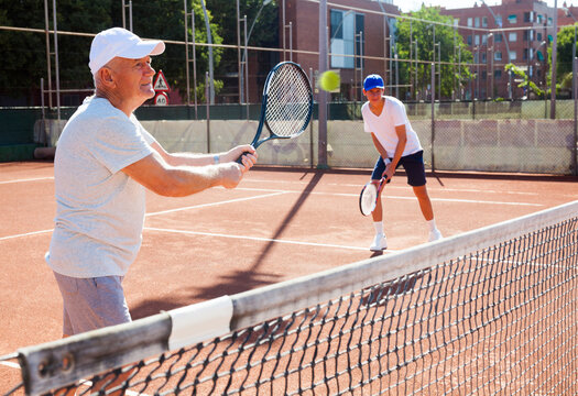 Grandfather and grandson playing tennis court