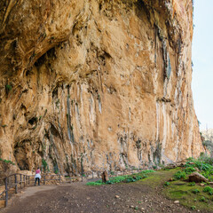 Hiking woman standing in large prehistoric cave Grotta dell'Uzzo at the Zingaro Nature Reserve, San Vito Lo Capo, Sicily, Italy