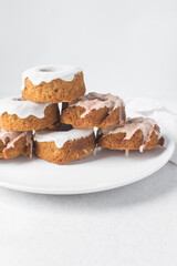 Iced mini bundt cakes on a white plate, vanilla bundlette with a clementine segment on a plate, small vanilla bundt cakes with an icing glaze