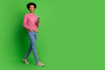 Full length photo of funky cool guy dressed pink pullover typing modern gadget walking emtpy space...