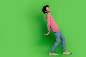 Full length photo of funky cool guy dressed pink pullover holding back emtpy space isolated green...