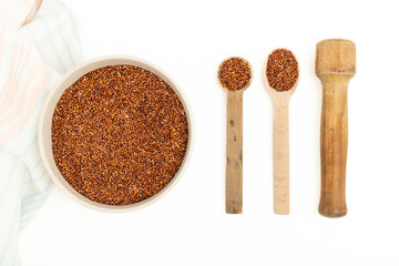Dry chia seeds in a bowl and wooden utensils on a white background