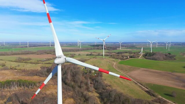 drone footage of wind turbines in a wind farm generating green electric energy on a wide green field on a sunny day, in Taurage, Lithuania