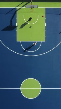 Vertical Screen: Capturing aerial footage of basketball players on a court is perfect for showcasing sports visuals, portraying movement, competition, action, and athleticism in team sports