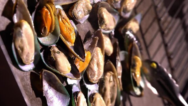 Chefs prepare clams in a restaurant in the open air in the evening.