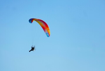 Man paragliding high in the blue sky with colorful parachute