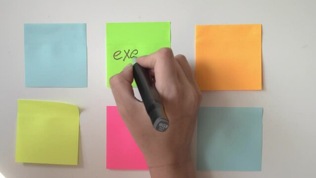 Hand writes Exam on yellow sticky note