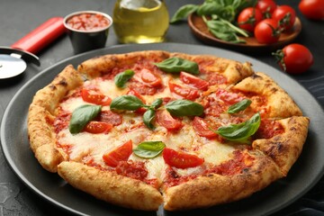 Delicious Margherita pizza, ingredients and cutter on black table, closeup
