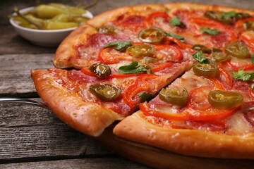 Delicious pizza Diablo and pickled peppers on wooden table, closeup