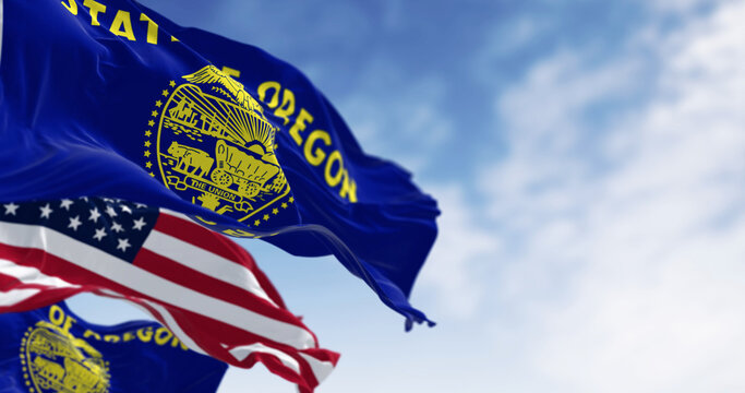 Oregon state flag waving in the wind with the american flag on a clear day