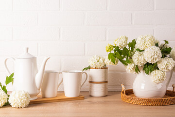 Modern kitchen background in light colors. A set of items for morning coffee on a wooden countertop. A spring flowering branches in a jug. Front view.