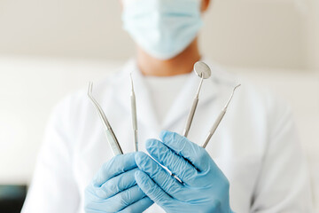 Professional dentist doctor wearing white coat, latex gloves holding sterile dental instruments